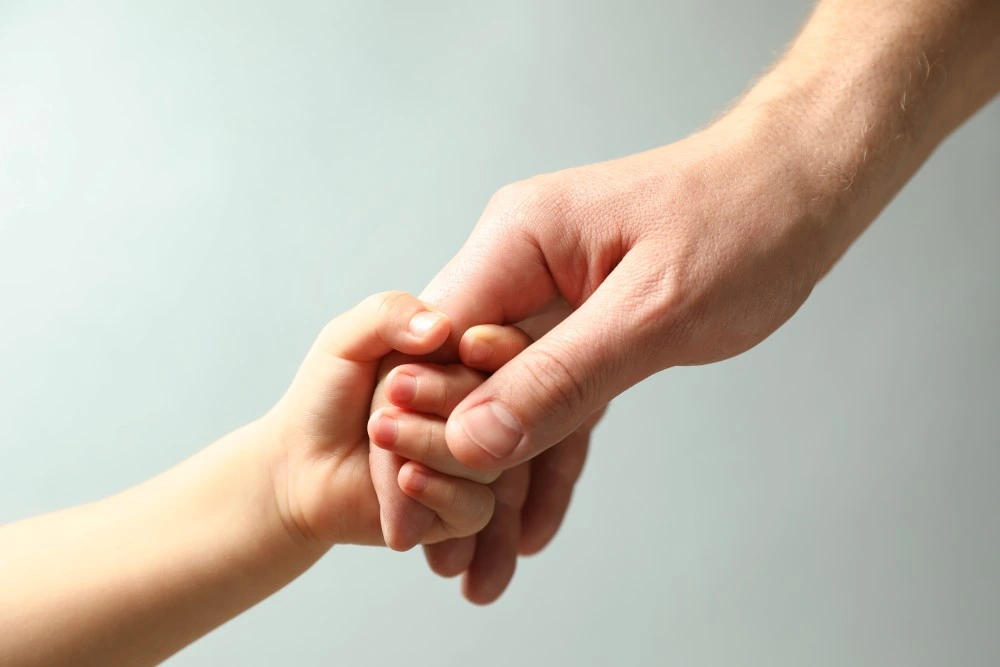 Adult hand holding a child's hand
