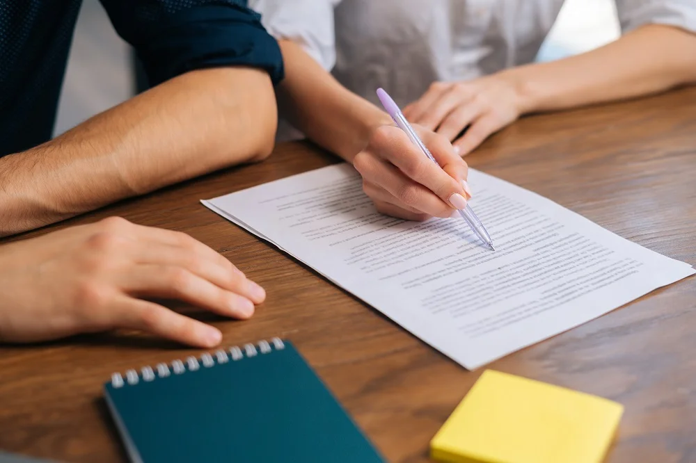 Two parents reviewing and signing an agreement at a table