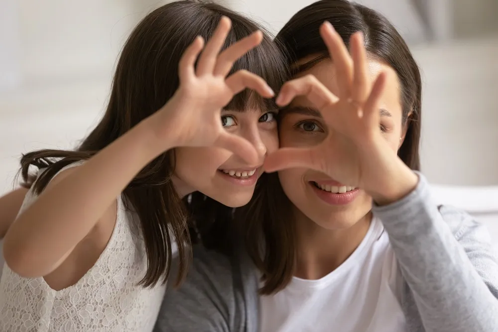 Mother and daughter making heart shapes with their hands