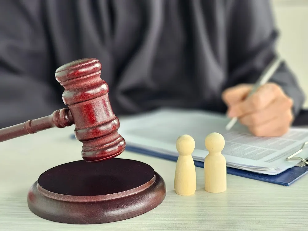 Gavel beside two wooden figures as a judge signs a document