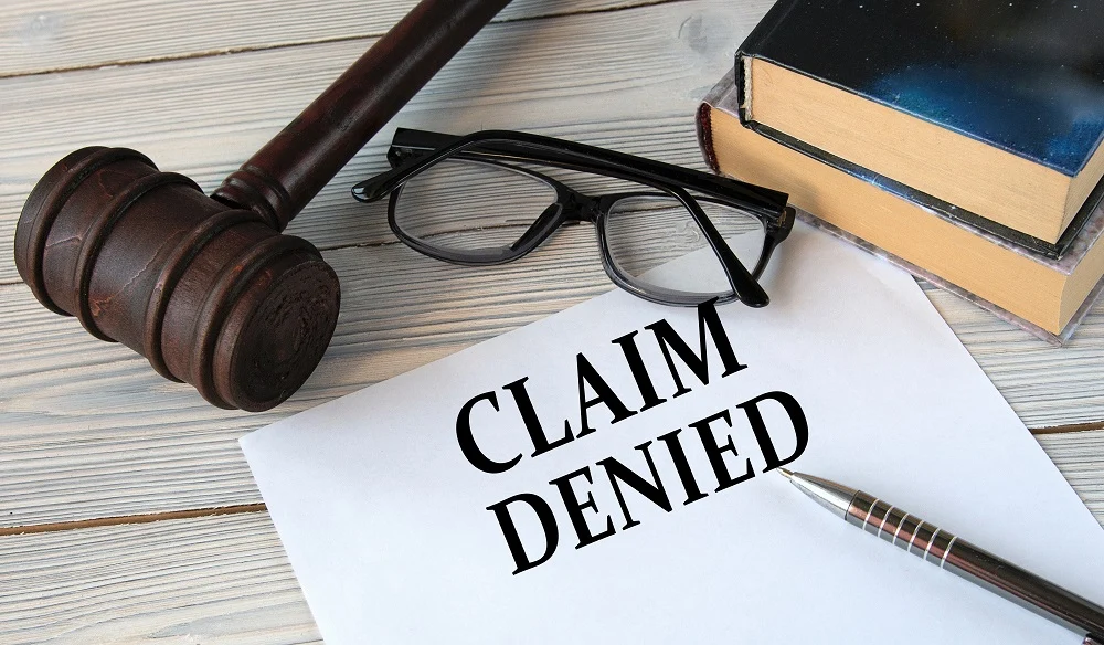 Gavel, glasses and a paper reading "Claim denied"