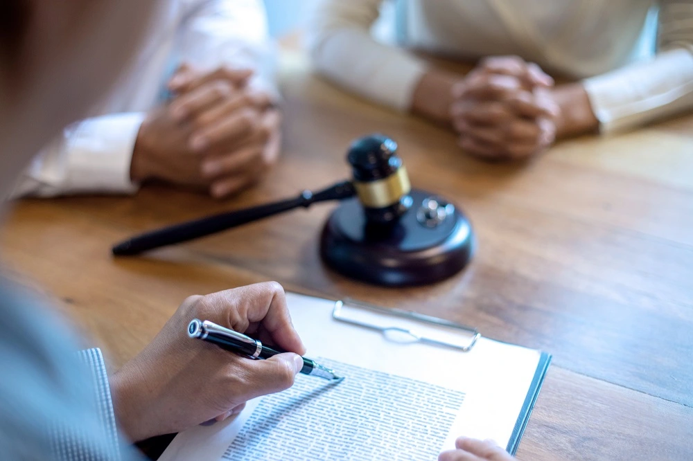Spouses signing legal separation papers beside a gavel