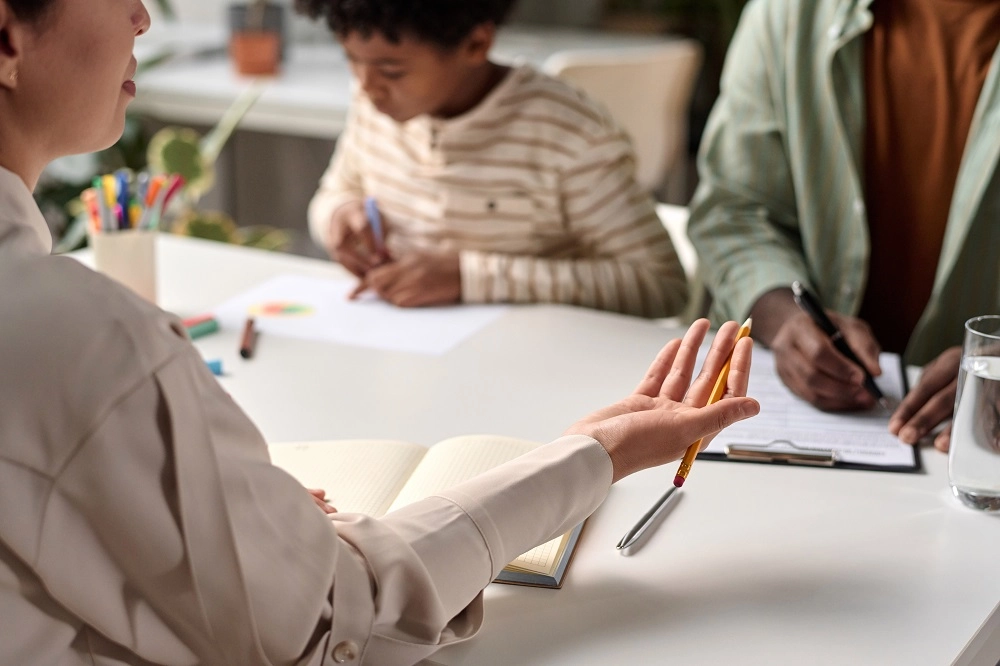 Guardian ad litem talking with a parent while a child draws at the table