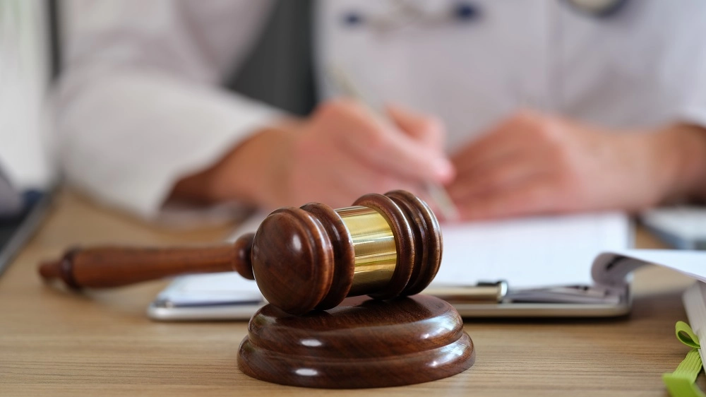 Gavel on a desk as a person writes in the background
