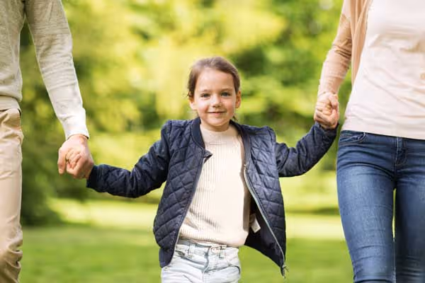 Parents holding hands with their daughter in a park