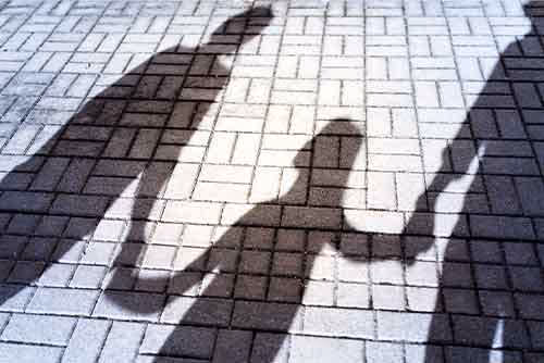 Shadow of a parent holding a child's hand on pavement