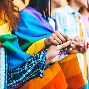 People holding hands over a rainbow flag