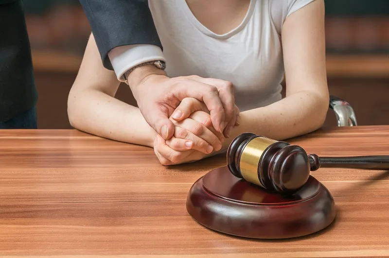 Couple's clasped hands on a table beside a gavel
