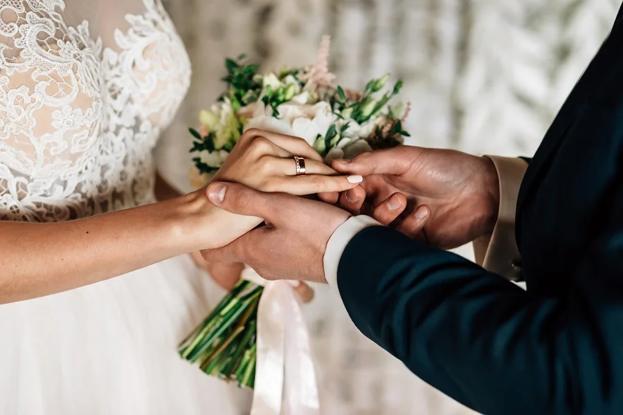 Bride and groom holding hands with a bouquet